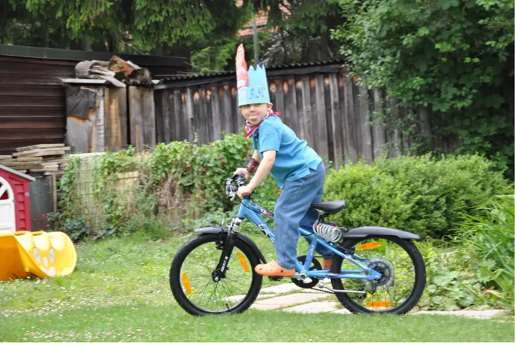 Ein stolzes Geburtstagskind mit Krone düst mit seinem neuen Mountainbike durch den Garten. Das Rad passt perferkt.