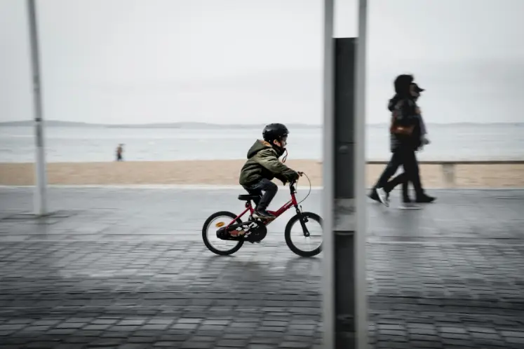 Kleines Kind radelt mit 16 Zoll Fahrrad durch eine Galerie am Stadtstrand. Die Radgröße passt perfekt.